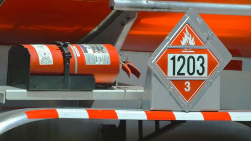 Flammable chemical container with hazard label and fire extinguisher on industrial truck for safety.