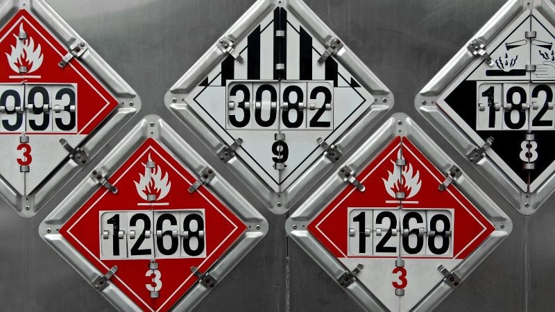 Dangerous chemical hazard warning signs for flammable and hazardous materials display in this industrial safety image, emphasizing the importance of proper handling and storage in compliance with safety regulations.
