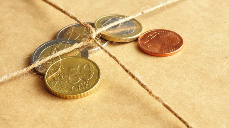 Euro coins on a tied brown paper package.